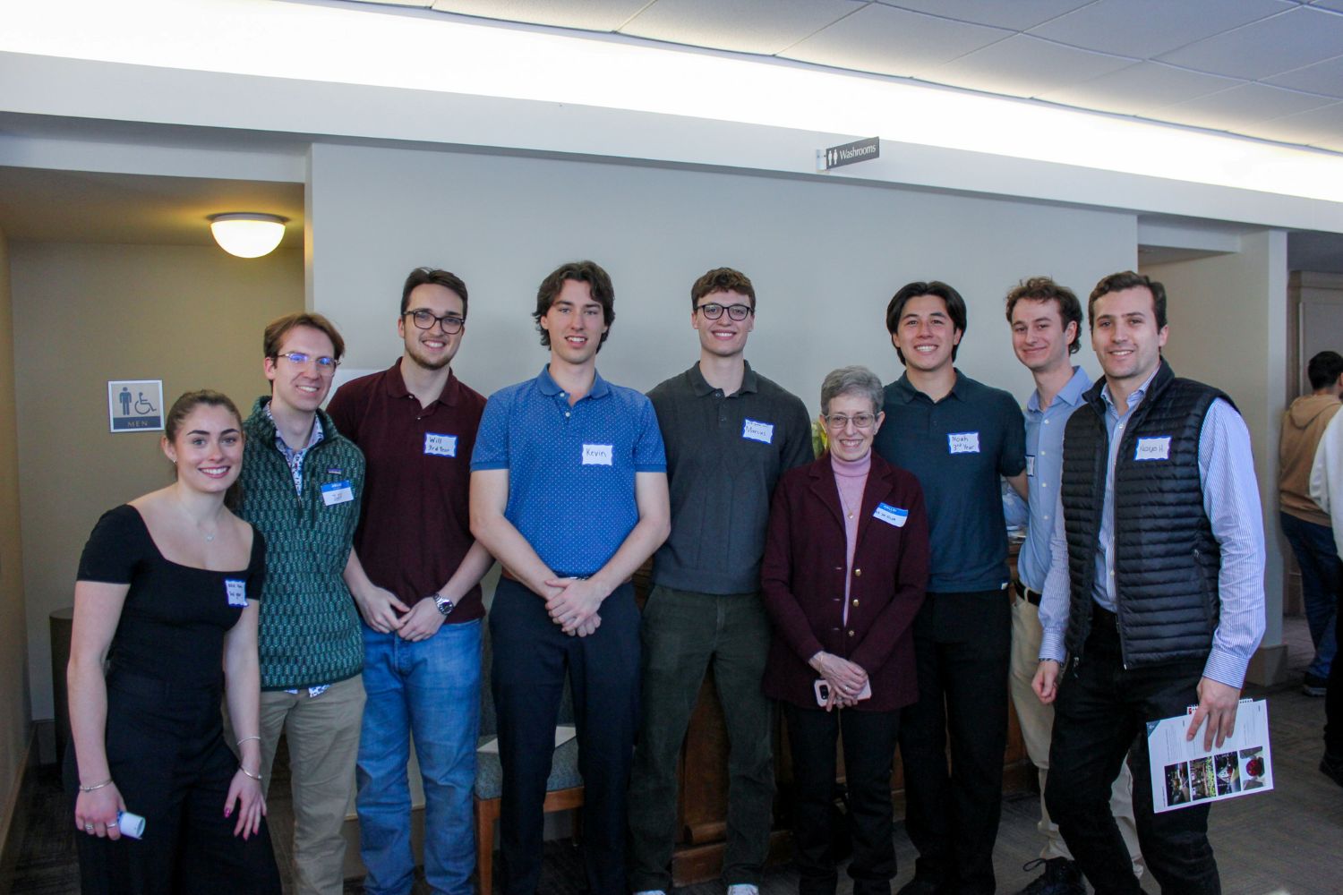 Group of people with name tags stand together and smile at camera