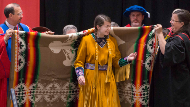 student getting Indigenous blanket placed on shoulders