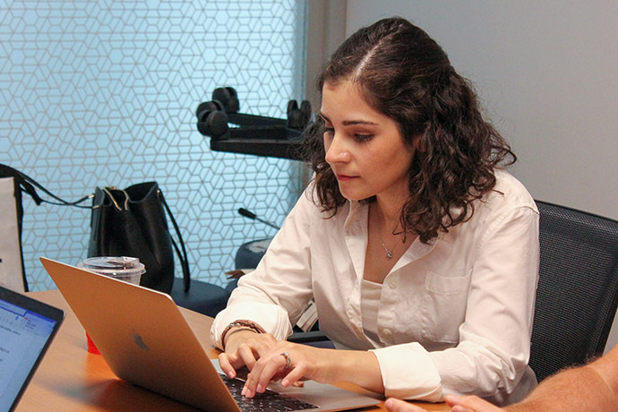 Woman working on a laptop at a table in an office