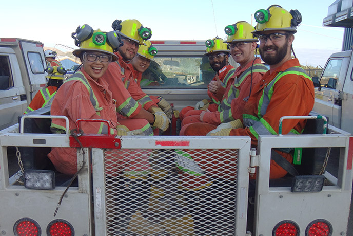 Mining engineering students in safety gear sitting in the back of a work truck