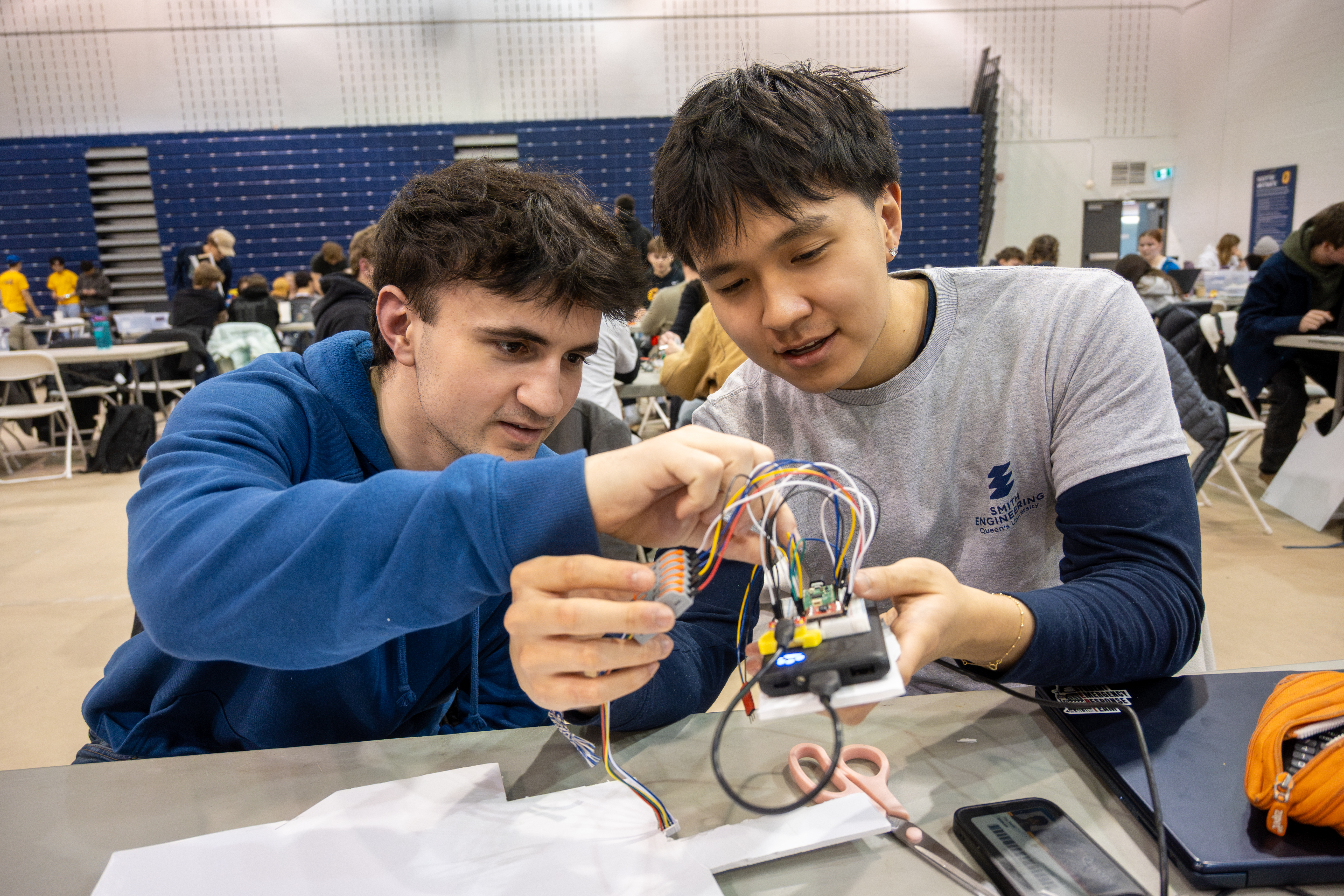 Two young me pour intently over a circuit board