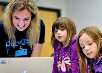 A woman with two children smiling in front of a computer