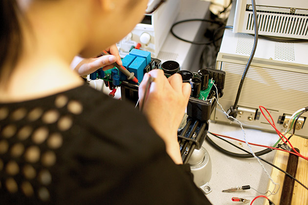 over-the-shoulder view of female researcher working on electronic component