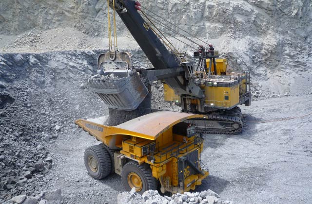 open pit mine looking down on a rope shovel loading material into a haul truck