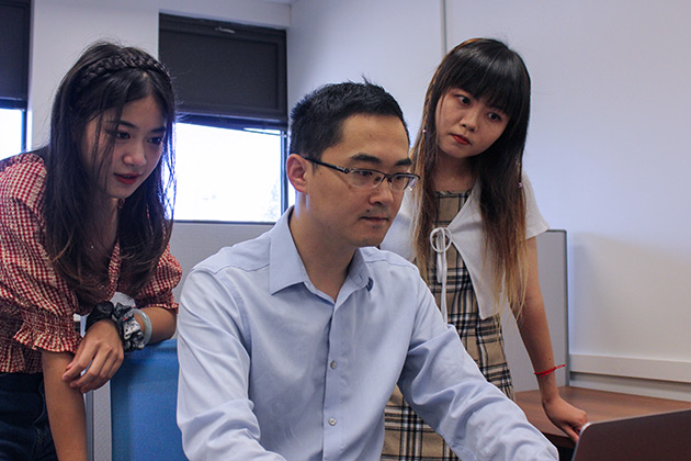female grad students looking at a laptop with male supervisor