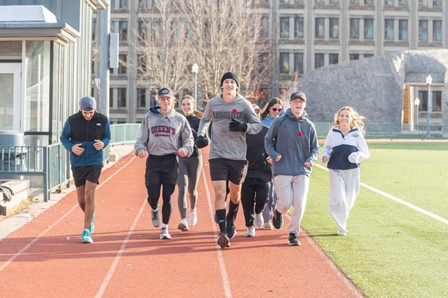 Students running in a group along a track. they all look very happy. 