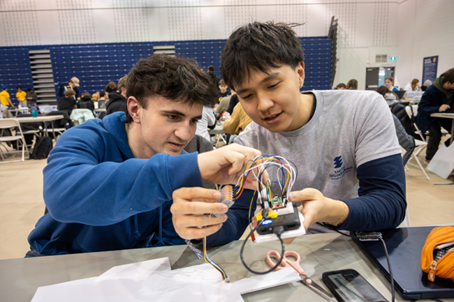 Two young men pour intently over a circuit board