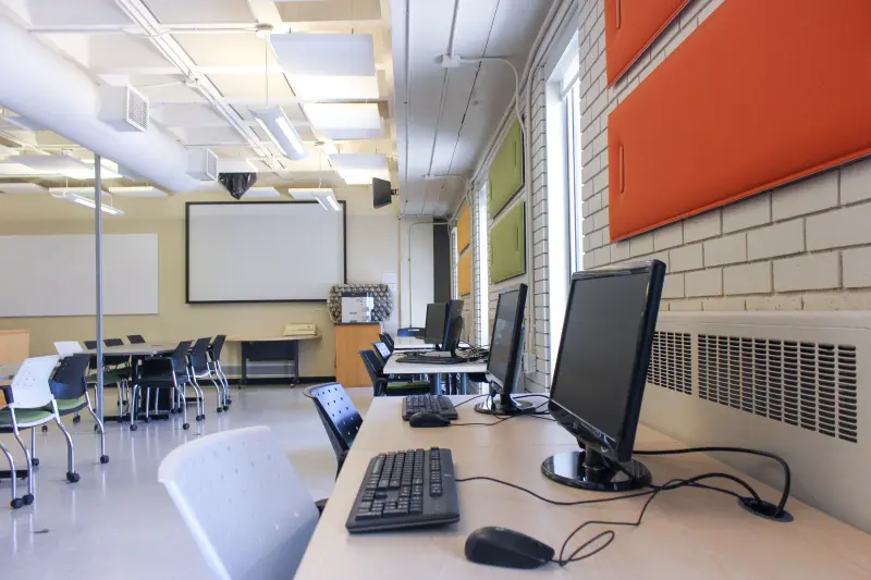 Modern classroom setup featuring computers on desks and colorful soundproof panels on the walls.